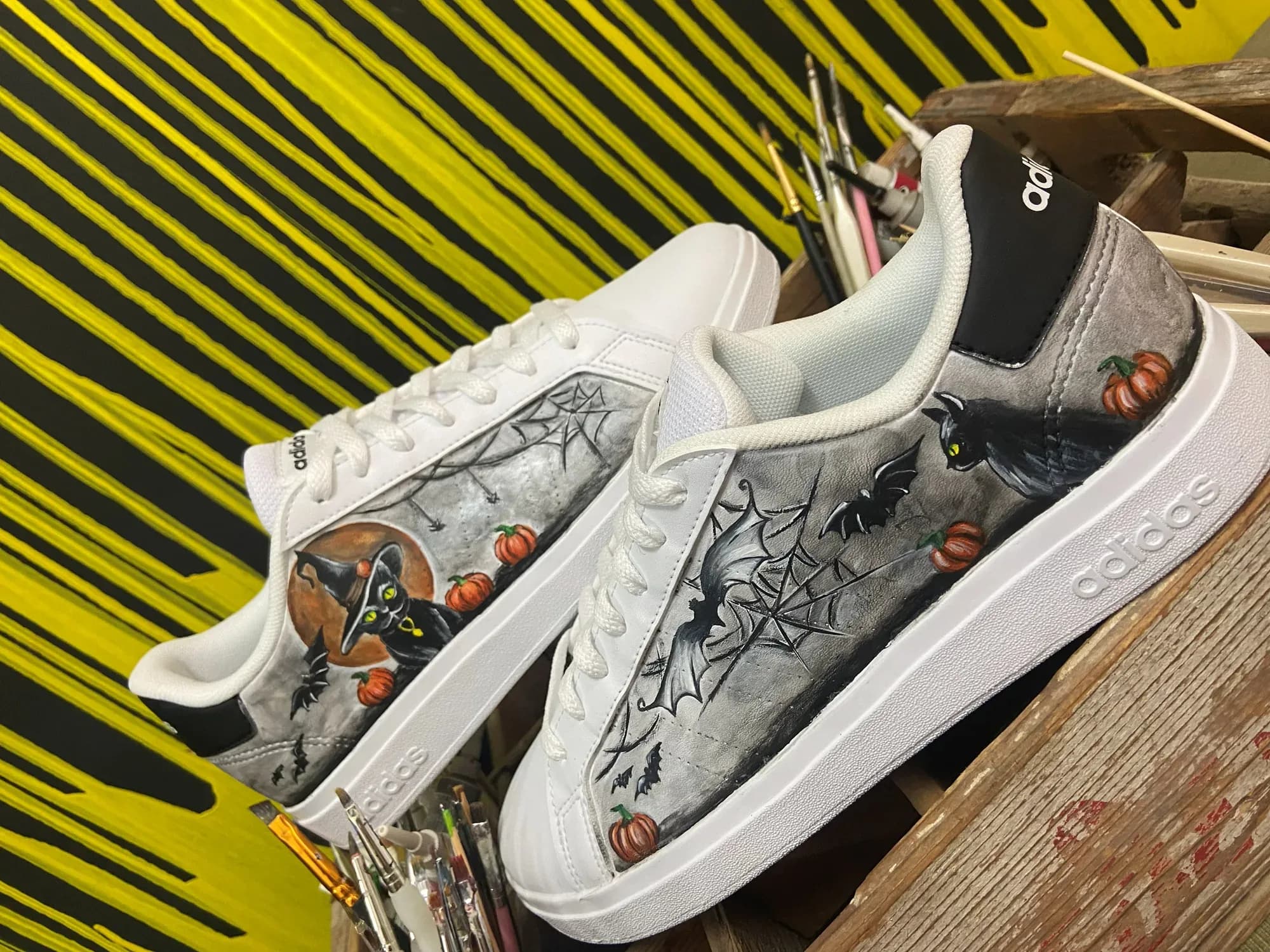 White sneakers hand-painted with a spider web and pumpkins for Halloween