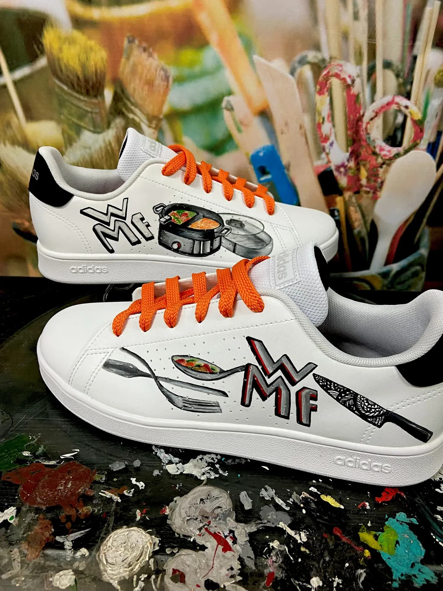 White sneakers hand-painted with cooking utensils and orange laces