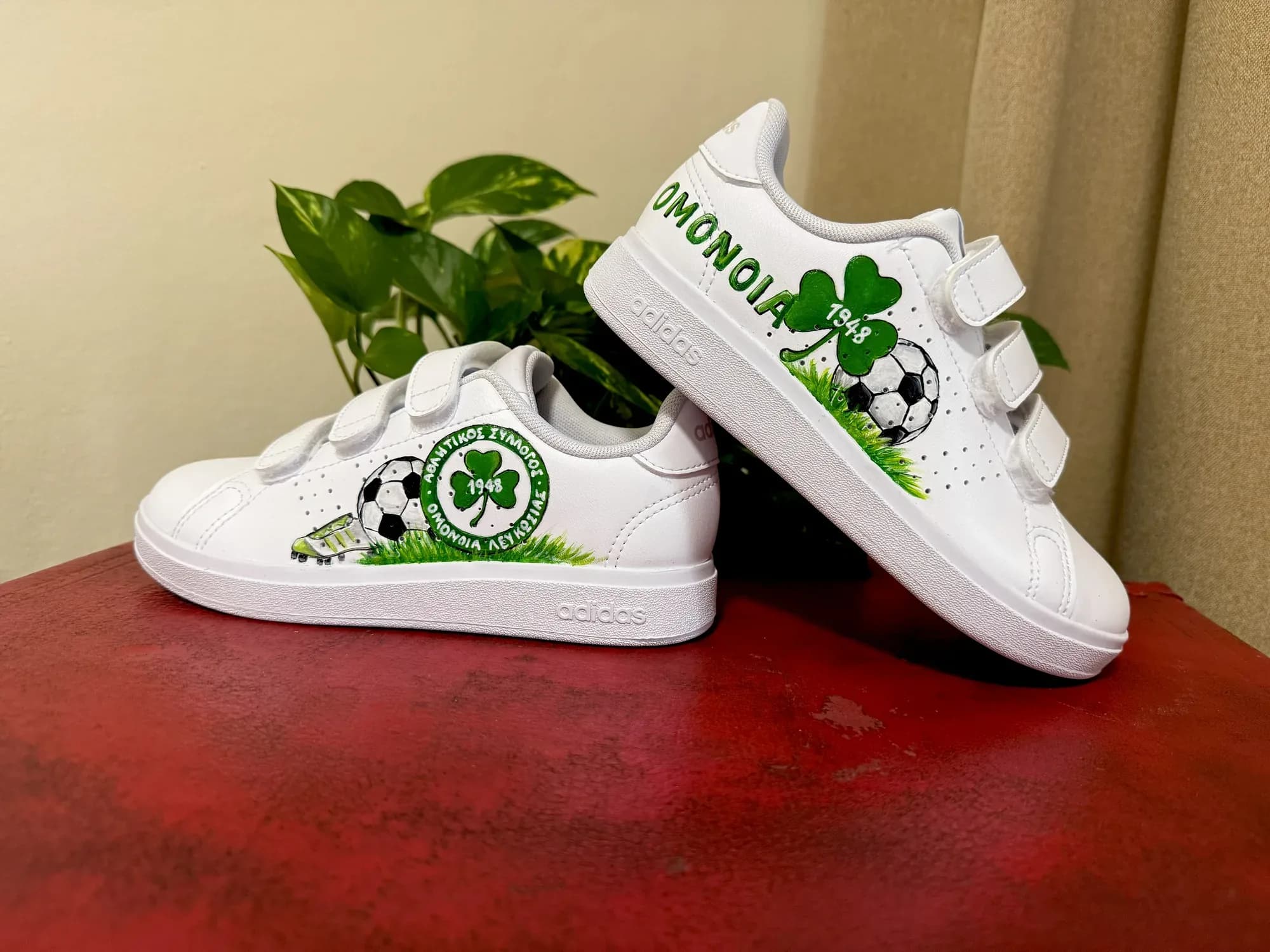White kids' velcro sneakers hand-painted with the Omonia clover, a football and grass