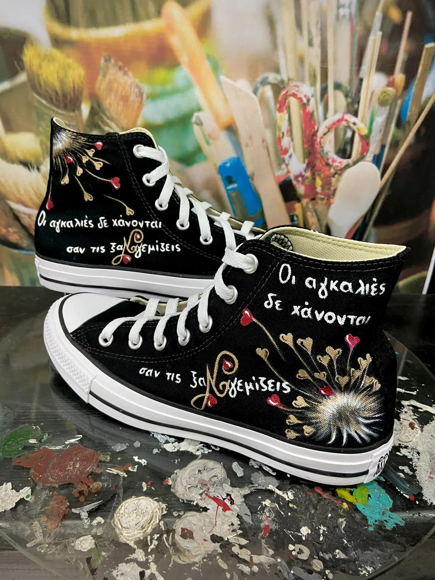 Black high-tops hand-painted with a dandelion and a Greek message about hugs