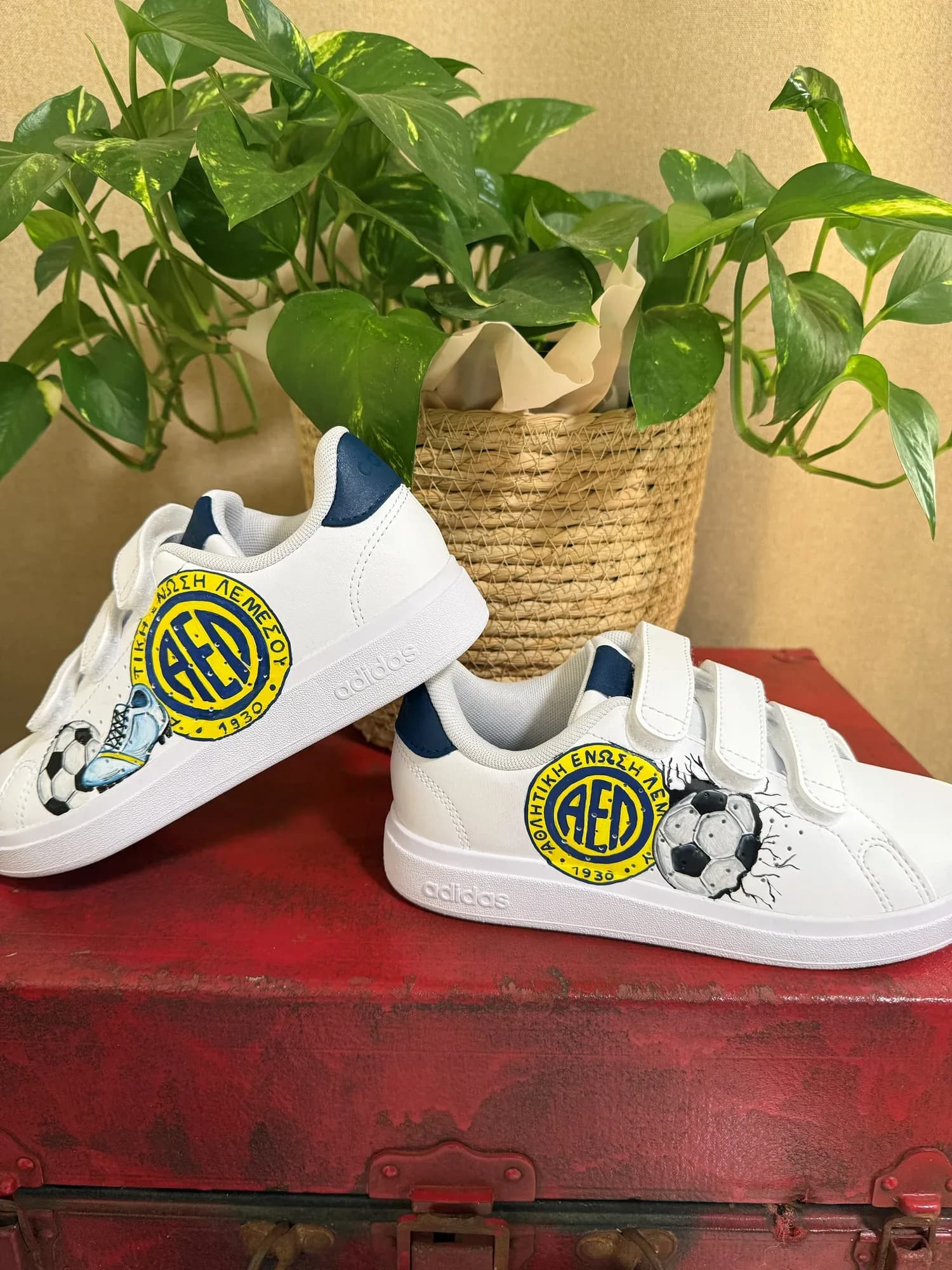White kids' velcro sneakers hand-painted with the AEL Limassol badge, a football and a boot