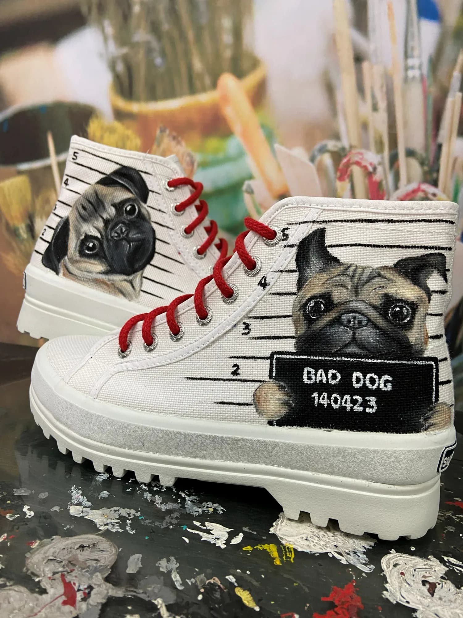 White boots hand-painted with a pug and a 'Bad Dog' sign