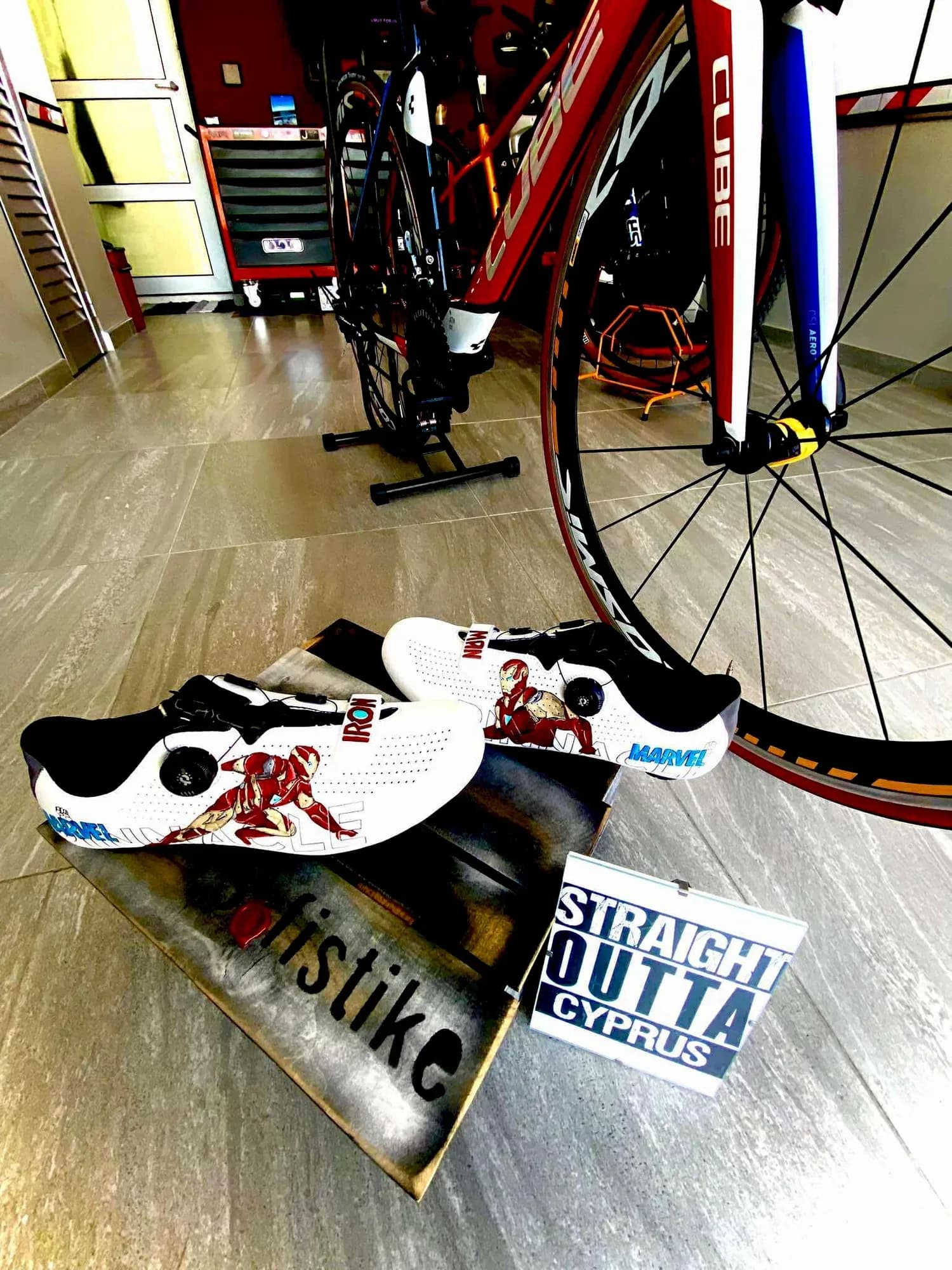 Cycling shoes hand-painted with Iron Man, next to a road bike
