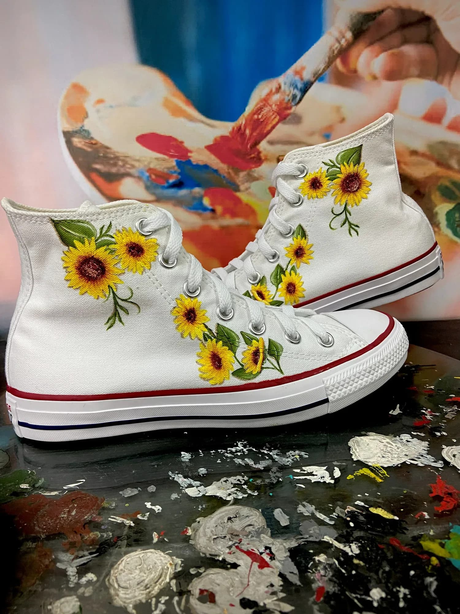 White high-tops hand-painted with sunflowers, next to a paint palette