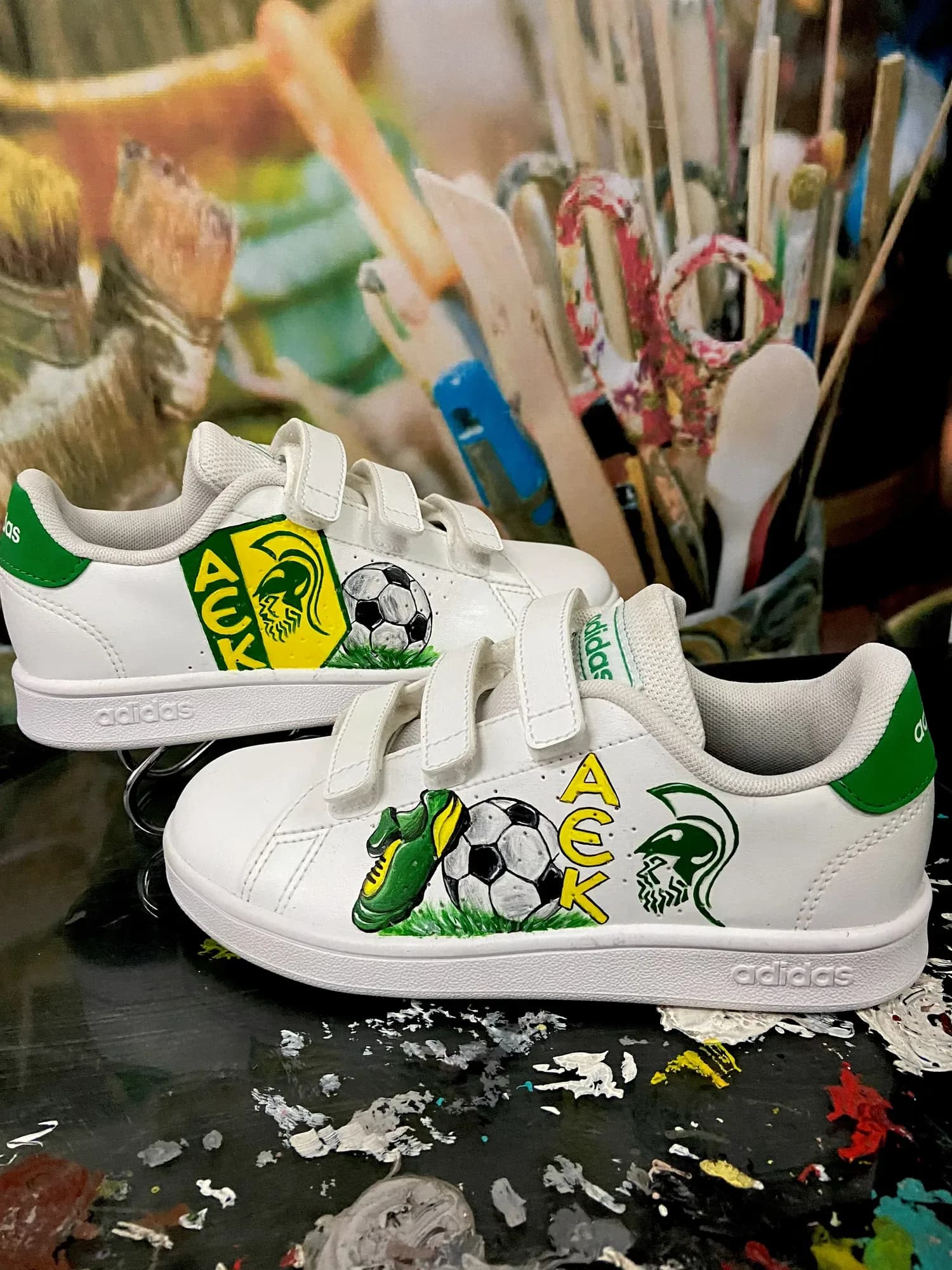 White kids' velcro sneakers hand-painted with an AEK badge, a football and a boot