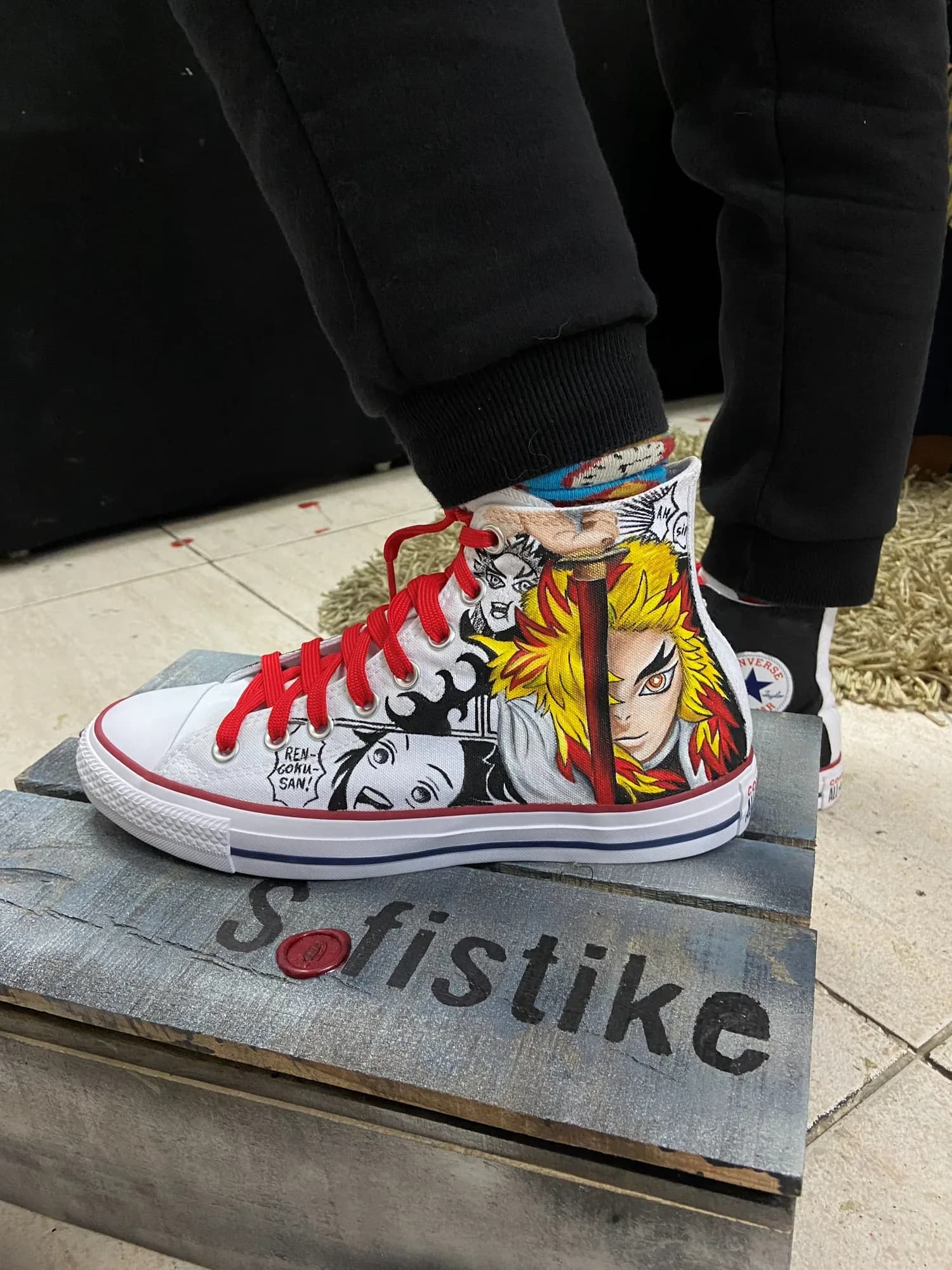 Worn white high-top with red laces, hand-painted with manga panels and an anime hero