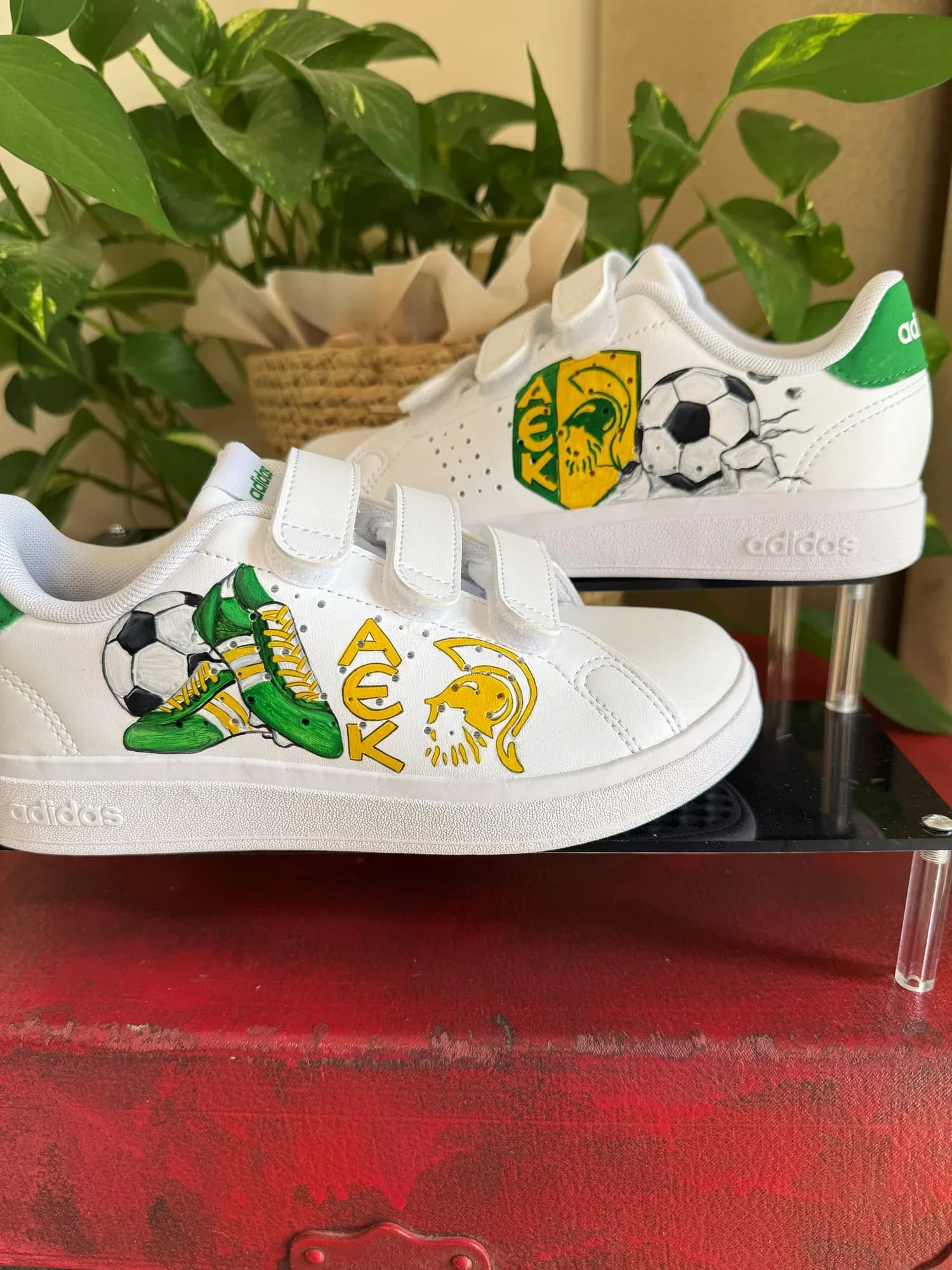 White kids' sneakers hand-painted with a green and yellow AEK badge with a helmet and a football