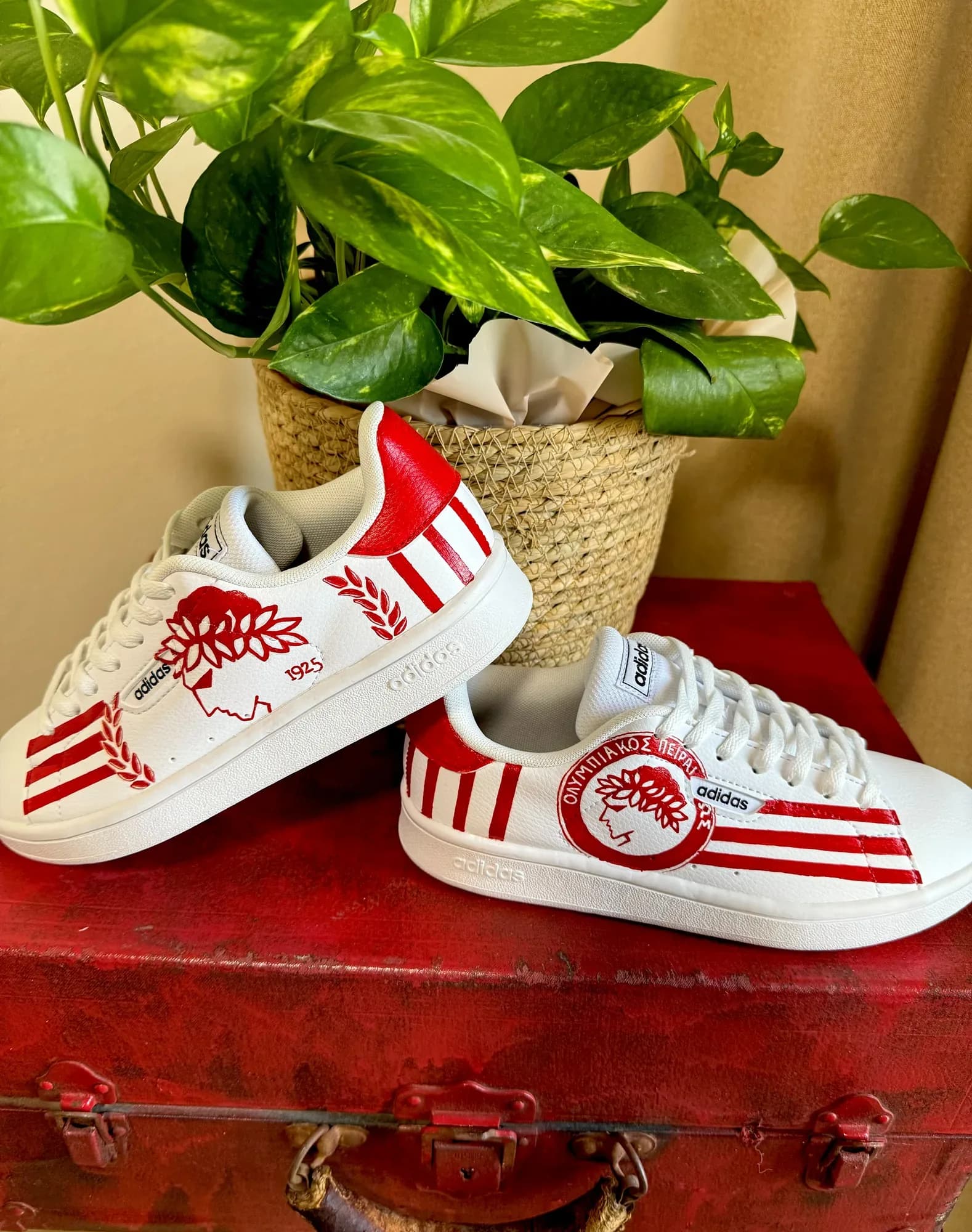 White adidas sneakers hand-painted with the Olympiacos badge, red stripes and a laurel wreath